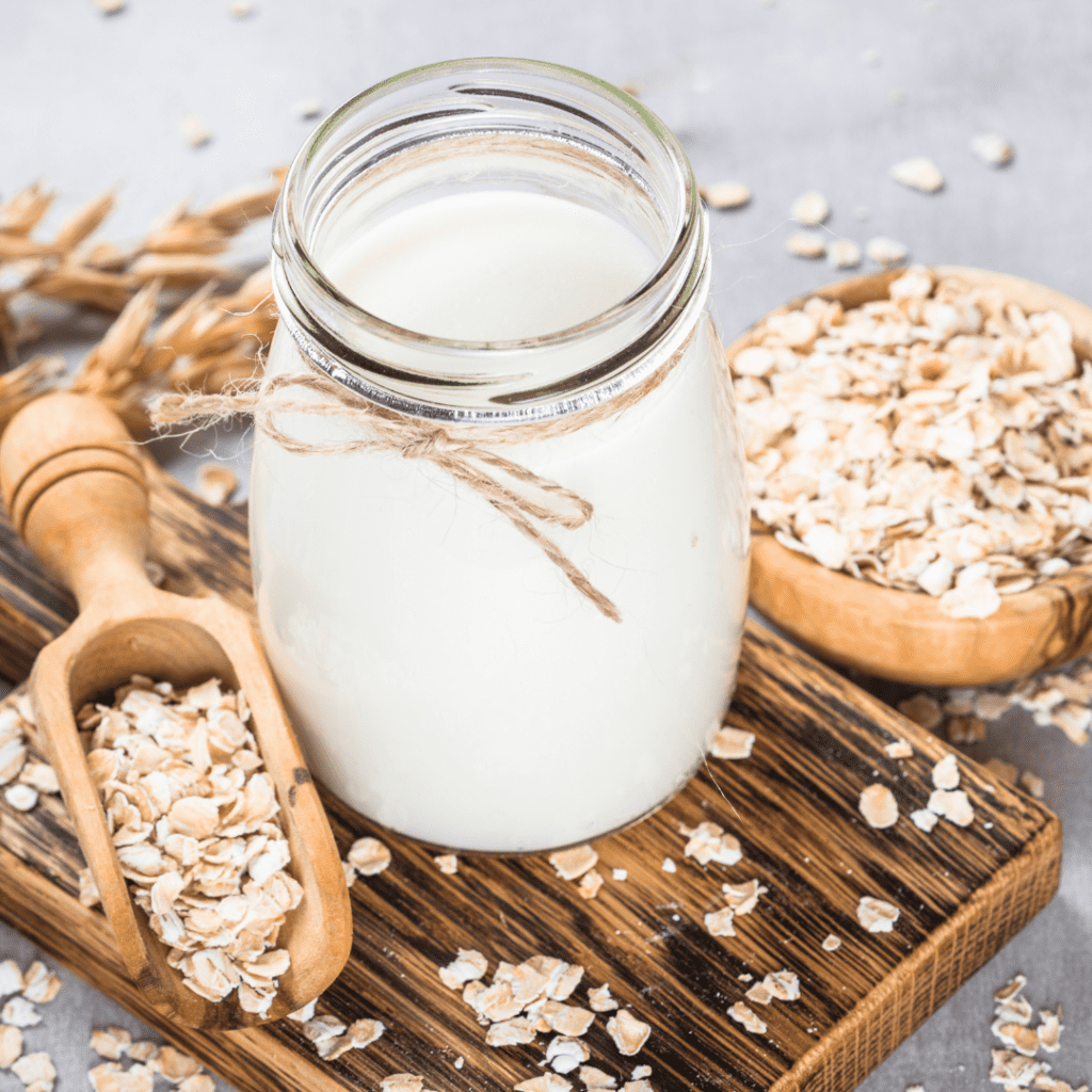 jar of oatmilk with oats and a scoop lying beside it